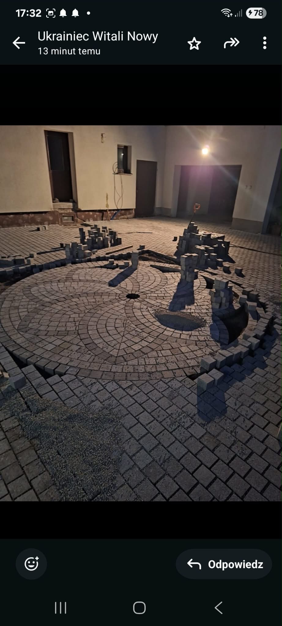 Układanie kostki brukowej w okrągły wzór na dziedzińcu. Częściowo ułożona nawierzchnia z kostki, widoczne przygotowane stosy kostki i narzędzia.