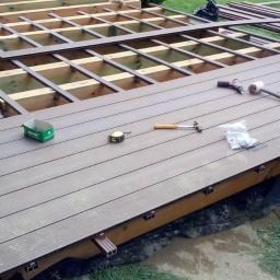 Aletaras Sławomir Klimek - Montaż tarasu z desek kompozytowych: widoczny szkielet konstrukcji, deski tarasowe, wkrętarka, młotek, miarka i inne narzędzia.