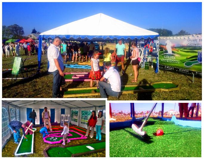 Mobilne pole do mini golfa pod namiotem, z ludźmi grającymi w plenerze, na tle zieleni i błękitnego nieba, z widocznym banerem reklamowym Golfin.