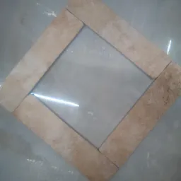 Układ płytek w kształcie rombu, beżowe, matowe wykończenie, widoczny fragment podłogi z połyskiem.