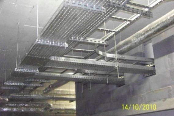 Sufit z zamontowanymi, perforowanymi korytkami kablowymi w szarym pomieszczeniu technicznym. Widoczne rury wentylacyjne. Data na zdjęciu: 14/10/2010.