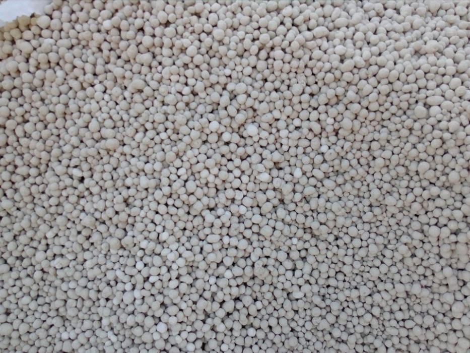 Gęsta warstwa jasnoszarych, granulowanych kuleczek, prawdopodobnie nawozu, wypełniająca całą klatkę.