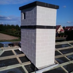 Zakład Usług Ogólnobudowlanych Mirosław Majtyka - Wzniesiony z białej cegły komin z czarnymi akcentami, widoczny na tle nieba i częściowo wykończonego dachu z membraną i drewnianą konstrukcją.