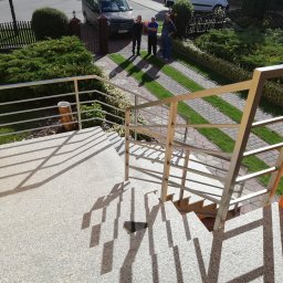 ALU-STAL - Zewnętrzne schody z jasnego granitu z nowoczesną balustradą ze stali nierdzewnej, widok z góry na ogród i trzech mężczyzn przed domem.