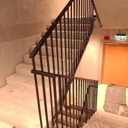 ALU-STAL - Nowoczesne schody z metalową balustradą w Wągrowcu. Minimalistyczny design, betonowe ściany, widoczne zabezpieczenia podłogi. Solidne wykonanie.