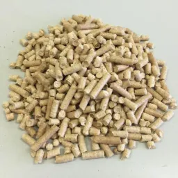 Jasne, cylindryczne brykiety pelletu drzewnego ułożone w stos na gładkiej, jasnej powierzchni. Widoczne detale tekstury i kształtu poszczególnych elementów.