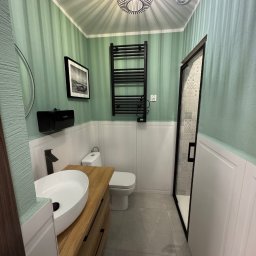 Patryk Gembara - Stylowa łazienka w Ostrava, Moravská Ostrava z umywalką na drewnianym blacie, grzejnikiem drabinkowym i kabiną prysznicową. Ściany w odcieniach zieleni i bieli.