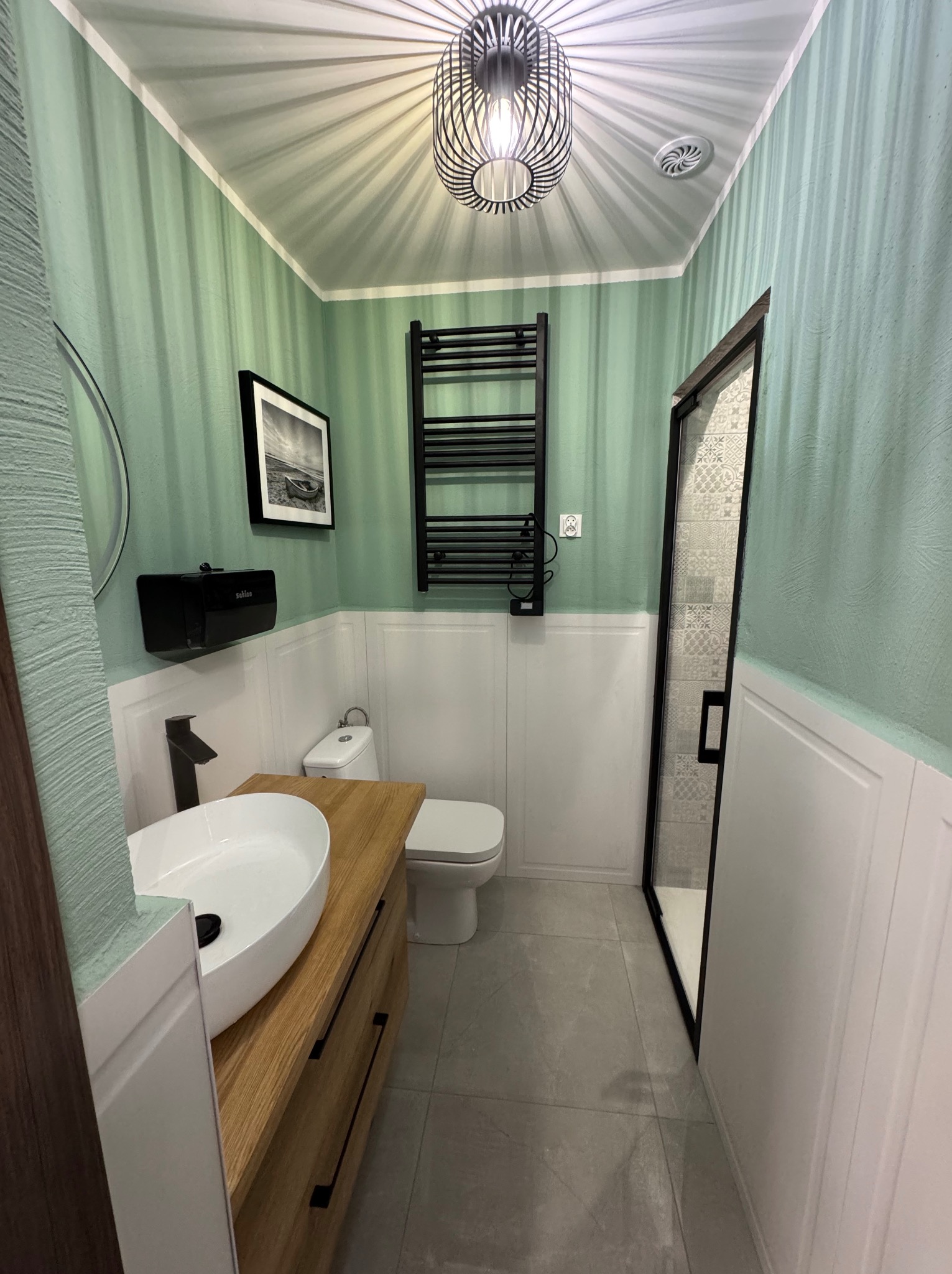 Stylowa łazienka w Ostrava, Moravská Ostrava z umywalką na drewnianym blacie, grzejnikiem drabinkowym i kabiną prysznicową. Ściany w odcieniach zieleni i bieli.