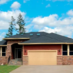 Dwukondygnacyjny dom jednorodzinny z garażem, wykończony kamieniem i drewnem, z dwuspadowym dachem i dwoma oknami dachowymi, na tle błękitnego nieba z chmurami.