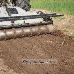 Elyzjum Sp. z o.o. - Ciągnik z mulczerem w trakcie pracy na polu, widoczne świeżo zmielone resztki roślinne i ślady opon.