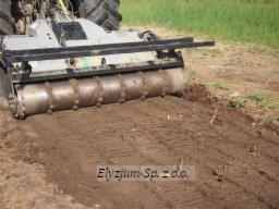 Ciągnik z mulczerem w trakcie pracy na polu, widoczne świeżo zmielone resztki roślinne i ślady opon.