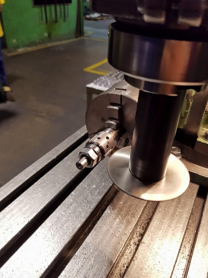 Precyzyjna obróbka metalu na tokarce CNC z widocznym uchwytem i obrabianym elementem. Detal w trakcie procesu toczenia, blask metalu, surowy warsztat.