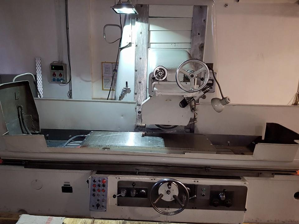 Szlifierka do metalu z widocznymi pokrętłami, lampką i elementami sterującymi. Widoczne ślady użytkowania na maszynie.