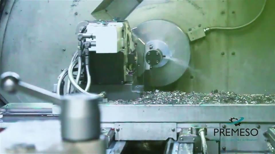 Praca tokarki CNC w trakcie obróbki metalu, widoczne opiłki i chłodziwo. W tle logo firmy Premeso.