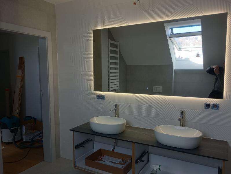 Nowoczesna łazienka z podwójną umywalką nablatową, podświetlanym lustrem i dekoracyjnymi płytkami ściennymi z geometrycznym wzorem.