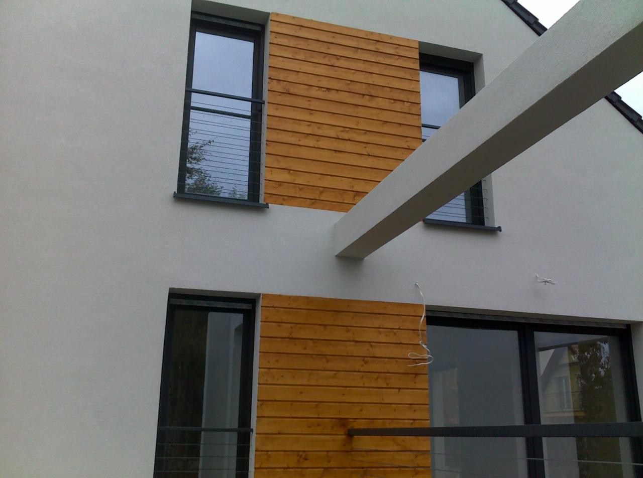 Nowoczesna fasada budynku z drewnianą okładziną między oknami, balkon z metalową barierką i biały, betonowy element architektoniczny.