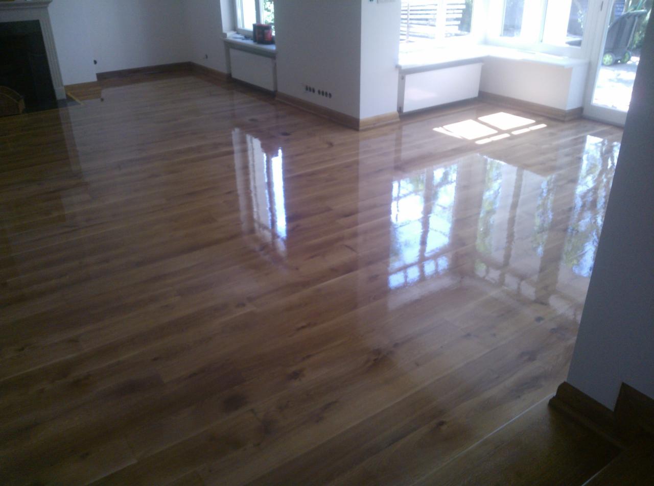 Błyszcząca, odnowiona podłoga drewniana w Kórniku, po cyklinowaniu. Widoczne refleksy światła od okien, podkreślające gładką powierzchnię.