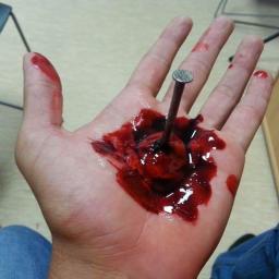 Żyrardowskie Powiatowe WOPR - Realistyczna rana dłoni z wbitym gwoździem, używana podczas symulacji urazów na kursie pierwszej pomocy. Krew i sztuczne uszkodzenia skóry.