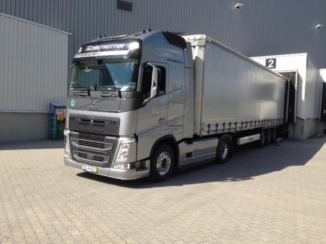 Srebrna ciężarówka Volvo z naczepą zaparkowana przy rampie załadunkowej z numerem 2. Widoczny napis 'Globetrotter' nad przednią szybą.