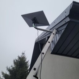 MICHALSKI MULTIMEDIA KRYSTYNA MICHALSKA - Antena satelitarna zamontowana na dachu domu w Bydgoszczy, widoczna drabina oparta o ścianę. Szara, pochmurna pogoda. Ujęcie z dołu.