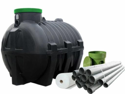 Czarny, plastikowy zbiornik z zieloną pokrywą, rury PCV związane sznurkiem, rolka białej włókniny i zielony element studzienki na białym tle.
