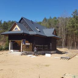BOA Rafał Duś - Dom jednorodzinny w trakcie montażu izolacji zewnętrznej, widoczne rusztowania, pracownicy oraz materiały izolacyjne na tle lasu.