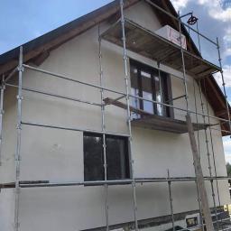 BOA Rafał Duś - Dom jednorodzinny w trakcie tynkowania elewacji, widoczne rusztowania i świeżo nałożony tynk w kolorze beżowym.