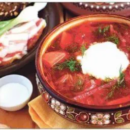 Apetyczny, gorący barszcz ukraiński w ozdobnej misce, z kleksem śmietany i koperkiem, obok pieczywo, boczek i zielony szczypior. Idealne danie na catering.