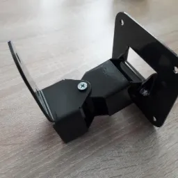 Czarny, metalowy, spawany uchwyt kątowy z otworami montażowymi, leżący na drewnianej powierzchni.