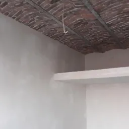 Ściana po nałożeniu gładzi, z widocznym fragmentem ceglanego łukowego sklepienia podtrzymywanego metalowymi belkami; widoczna półka z płyty karton gips.