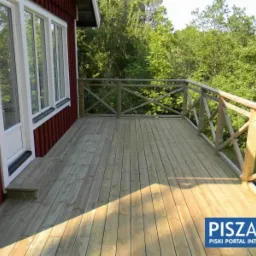 Wykończony drewniany taras z balustradą przy domu w Pisz. Naturalne drewno i solidna konstrukcja, widok na zieleń. Realizacja z dbałością o detale.