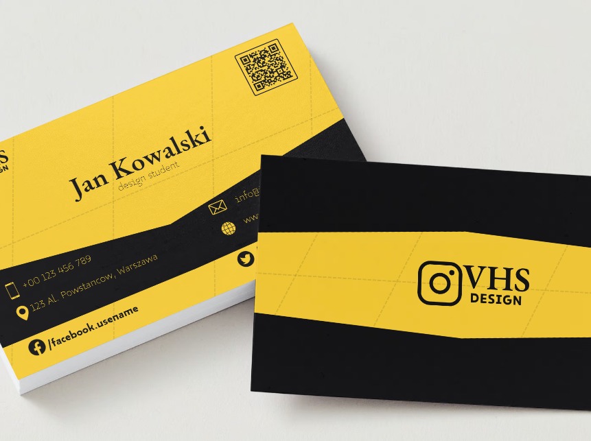 Stos wizytówek w kolorach żółto-czarnych, prezentujących dane kontaktowe i logo firmy VHS Design, z widocznym QR kodem na górnej wizytówce.