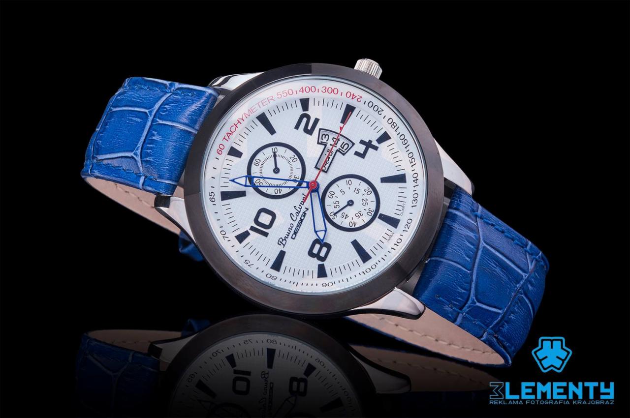 Precyzyjne ujęcie zegarka Bruno Calvani z niebieskim paskiem imitującym skórę krokodyla, na czarnym, lustrzanym tle, podkreślające detale tarczy i fakturę paska.