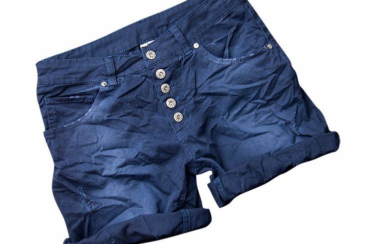 Niebieskie, dżinsowe szorty z wysokim stanem i ozdobnymi guzikami, leżące na białym tle, ukazane w zbliżeniu.