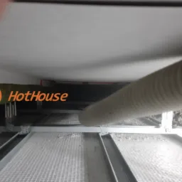 Widok z dołu na konstrukcję sufitu podwieszanego z widocznym kanałem wentylacyjnym i logiem firmy HotHouse