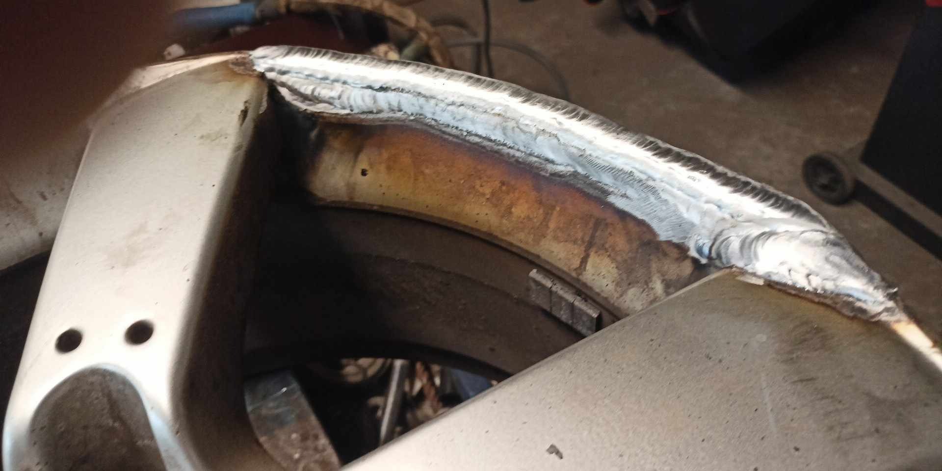 Spoina na metalowym elemencie konstrukcyjnym, widoczne ślady przypalenia i niedoskonałości spoiny.