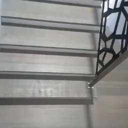 Jasne, drewniane stopnie schod&oacute;w z nowoczesną, geometryczną balustradą i widocznymi mocowaniami.