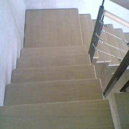 Drewkomplet Spółka z Ograniczoną Odpowiedzialnością - Beżowe schody z metalowo-drewnianą balustradą, widok z góry, neutralne oświetlenie, minimalistyczny styl, nowoczesne wykończenie.