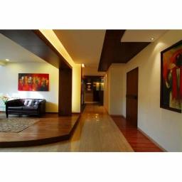 Drewkomplet Spółka z Ograniczoną Odpowiedzialnością - Nowoczesny korytarz z drewnianą podłogą i sufitem, oświetleniem LED oraz obrazami. Minimalistyczny design, eleganckie wykończenie, ciepła kolorystyka.