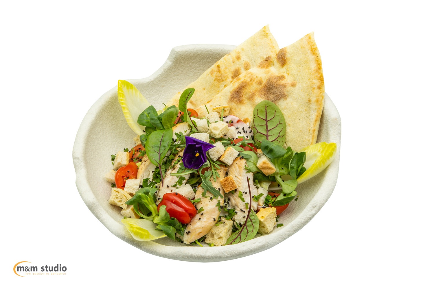 Apetyczna sałatka z grillowanym kurczakiem, pomidorkami, grzankami i jadalnymi kwiatami, podana z pitą w designerskiej misce na białym tle. Fotografia kulinarna.