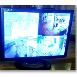 AVO technika sp z o o - Monitor CCTV marki Vilux wyświetlający obraz z czterech kamer, ukazujący wnętrze i otoczenie budynku. System monitoringu wizyjnego w zbliżeniu.