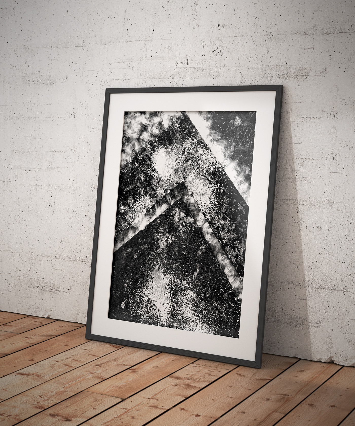 Czarno-biała grafika warsztatowa w ramie, oparta o szarą ścianę na drewnianej podłodze, przedstawiająca abstrakcyjną kompozycję z dominującymi trójkątnymi kształtami i kontrastowymi plamami.