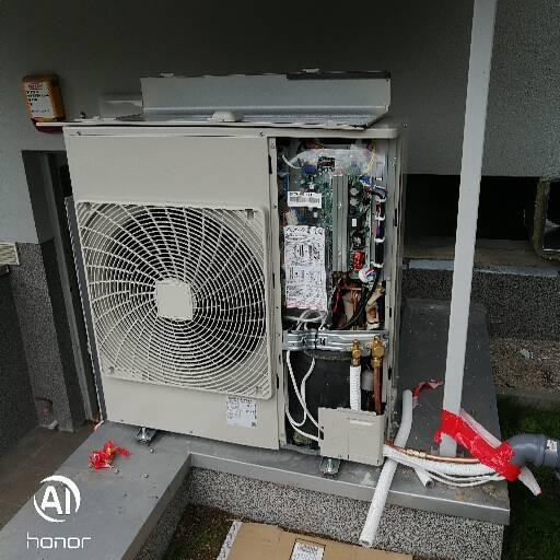 Otwarta obudowa urządzenia z widocznym wentylatorem i wewnętrznymi komponentami elektronicznymi oraz rurami, częściowo zabezpieczonymi czerwoną taśmą.