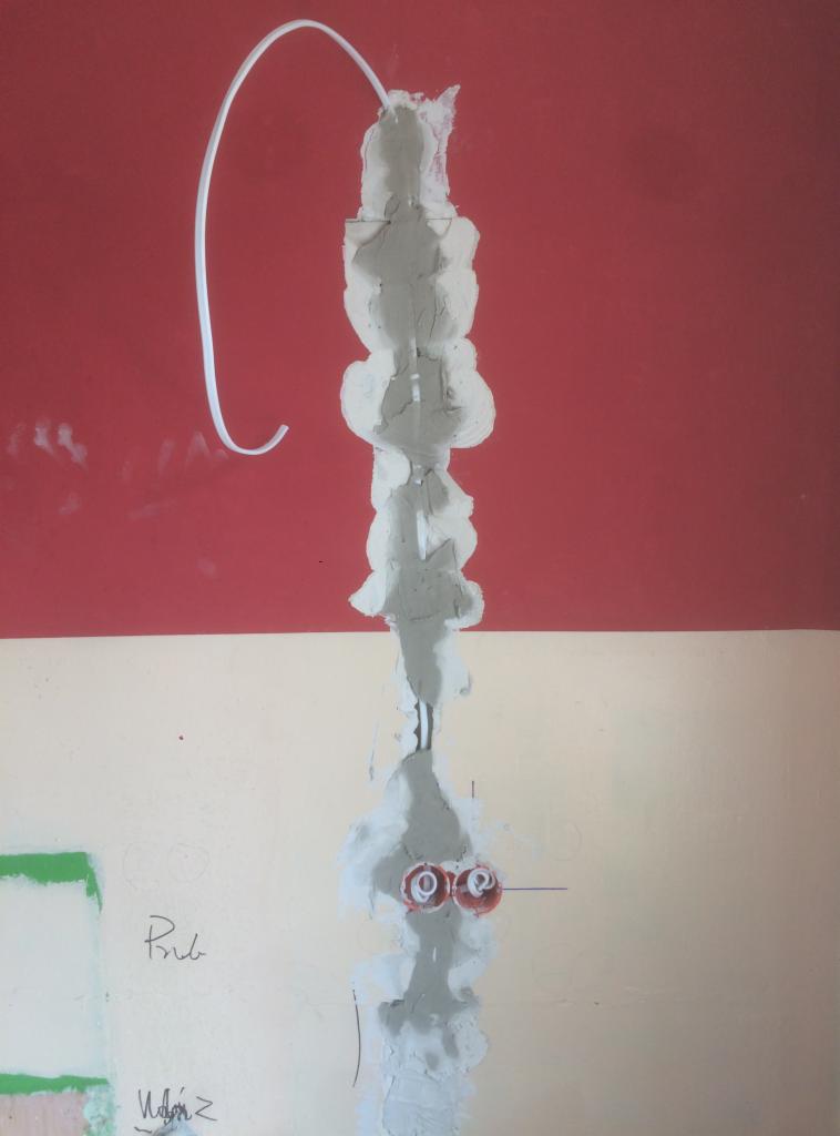 Ściana w trakcie prac wykończeniowych: widoczne dwie puszki elektryczne, kabel i ślady po szpachlowaniu na granicy dwóch kolorów farby.