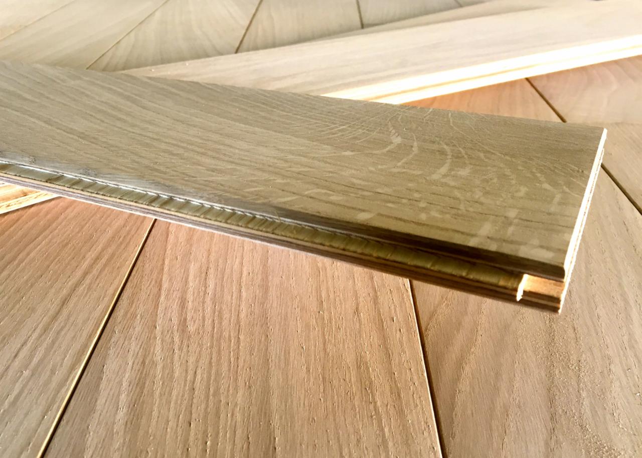 Fragment podłogi z desek dębowych, z widocznym systemem łączenia na pióro i wpust. Jasne drewno, ciepłe oświetlenie, zbliżenie na strukturę i detale wykończenia.