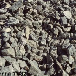 Kora kamienna o frakcji 11-32 mm: nieregularne, szaro-białe kamienie z widocznymi smugami, tworzące dekoracyjną nawierzchnię. Widoczne cienie podkreślają fakturę.