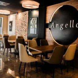 Wnętrze restauracji z ceglaną ścianą, drewnianym panelem z logo 'Angello', nowoczesnymi lampami sufitowymi i błyszczącą podłogą.