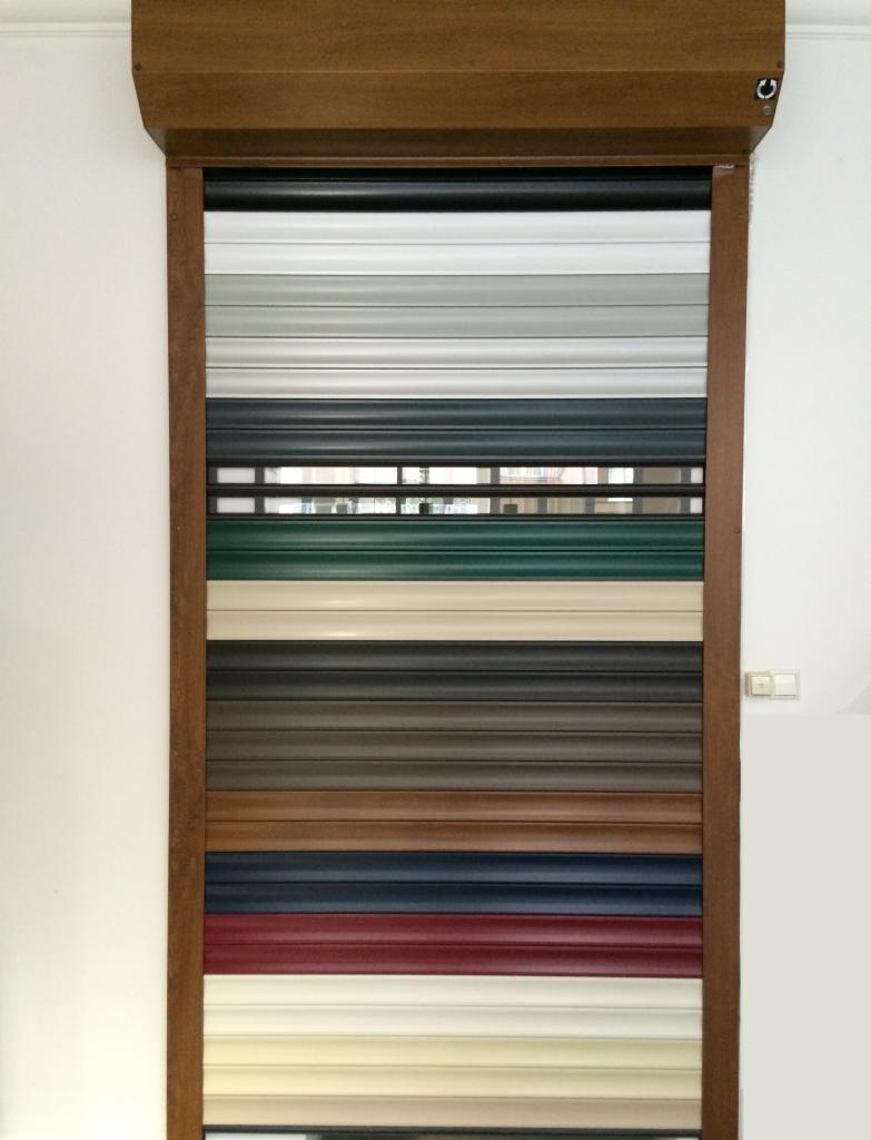 Paleta kolorów rolety zewnętrznej z drewnianą ramą. Widoczne poziome pasy w odcieniach bieli, szarości, zieleni, brązu, granatu i czerwieni. Prezentacja możliwości kolorystycznych.