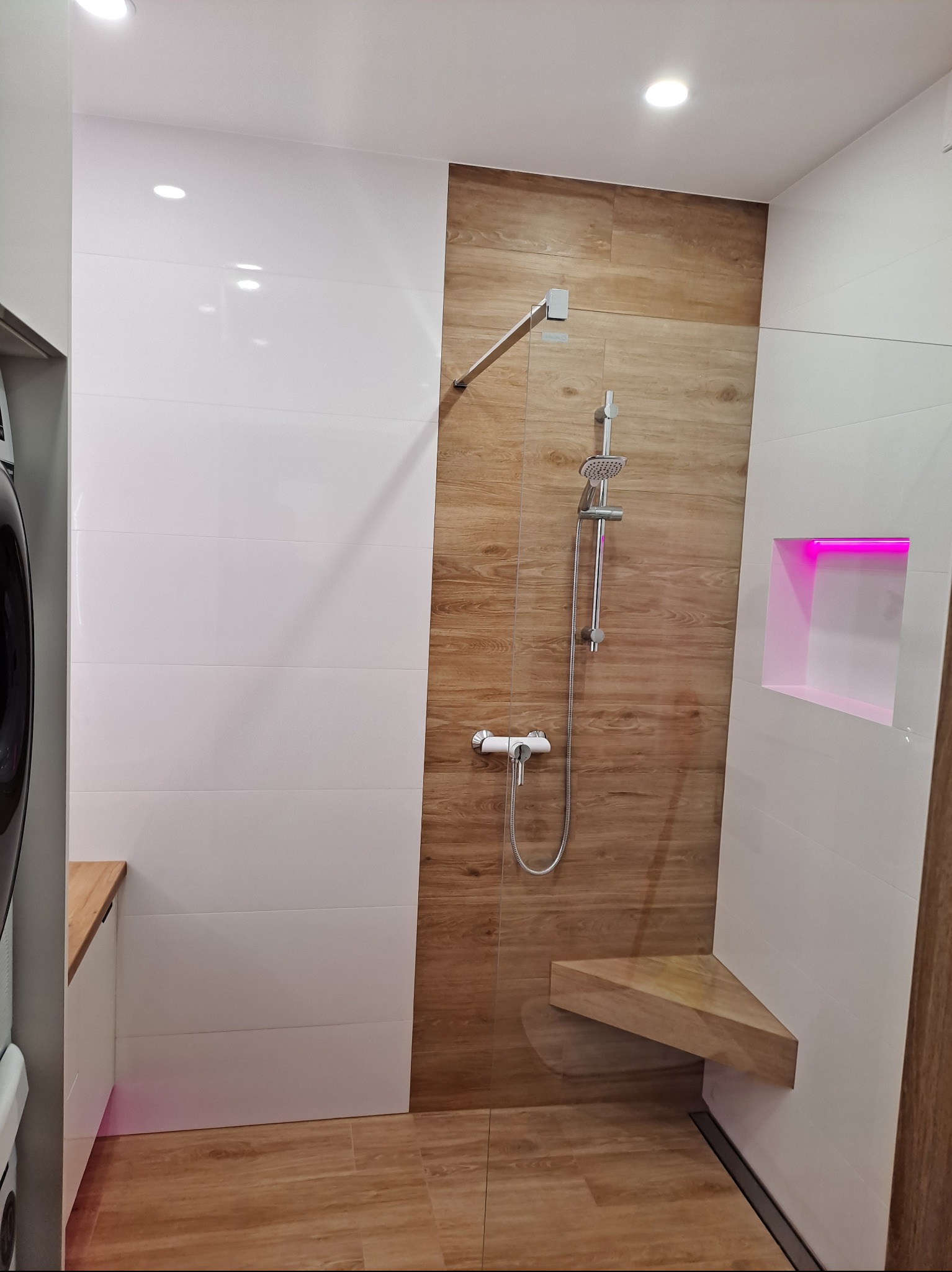 Nowoczesna kabina prysznicowa z drewnopodobnymi i białymi płytkami, siedziskiem i podświetlaną wnęką w Lęborku. Minimalistyczny design i funkcjonalność.