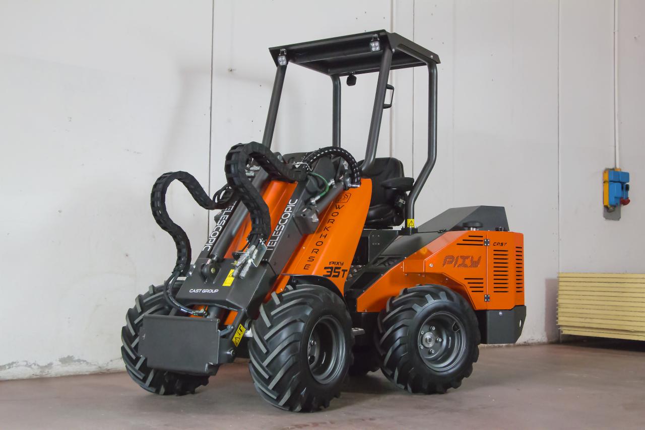 Pomarańczowa miniładowarka Pixy 35T z kabiną ochronną, widok z przodu na białym tle magazynu.